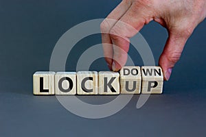 Lockdown or lockup symbol. Hand turns cubes and changes the word `lockup` to `lockdown`. Beautiful grey background. Copy space