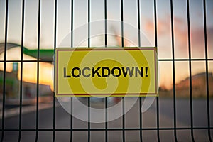 Lockdown sign on a fence with blured city view on a background at sunset photo