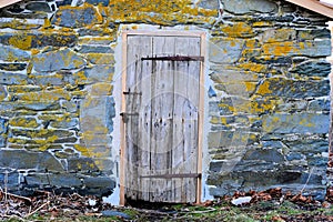 A locked barn board door on a stone building