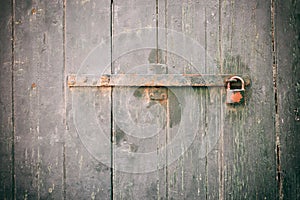 Locked door. Closed old rusty padlock on a weathered wooden door
