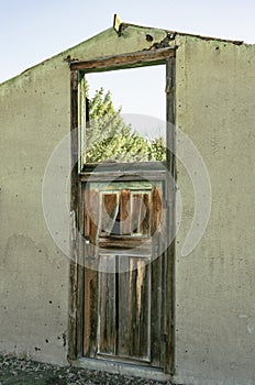 Locked door is topped with window opening to the sky. Old wall facade is in disrepair.