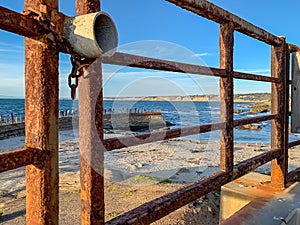 Locked gate in foreground of tourists on pier overlooking La Jolla Beach coves with sea lions