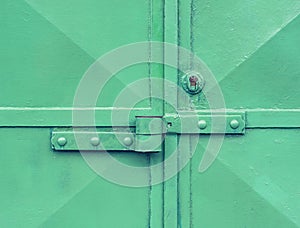 Locked green warehouse metal door. Detail view to locked latch