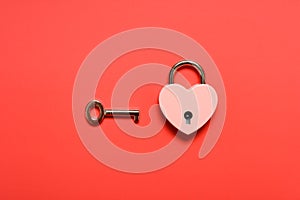 a locked heart shape padlock with key on a red background