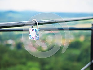 Locked lock hangs on the metal fence. Symbol of love in the park