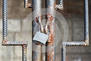 Locked lock old rusty metal door close up. Antique slide steel locked shutter door. The lock, on the grating, closed