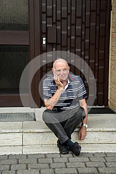 Locked out senior man sitting in front of his house