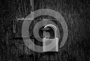 Locked padlock with chain at gray wooden door. black and white