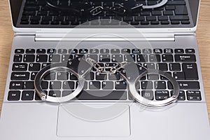 Locked pair of handcuffs on a laptop keyboard