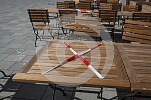 Locked table with red and white flutter band in a street cafe during the coronavirus crisis, keeping the prescribed social