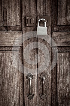 Locked wooden door with silver padlock