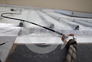 Locking Karabiner connecting into first man safety line up permanently attached onto roof safety anchor point photo