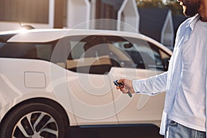 Locking the vehicle. Young stylish man is with electric car at daytime photo