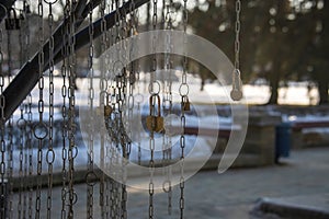 Locks threaded through chain links hanging in a city park. Loving couples hang locks on a chain as a symbol of the strength of