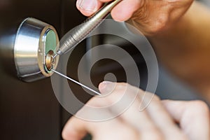 Locksmith hands using pick tools to open locked door