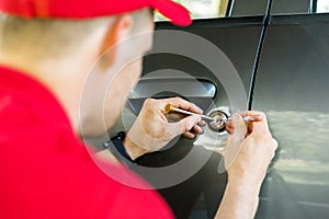 Locksmith opening car door with lockpicker photo