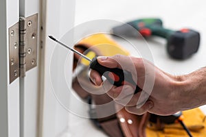 A locksmith is repairing an interior door lock. Close-up of male hands repairing or replacing an entrance door lock with