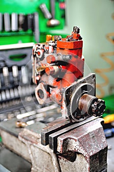 Locksmith repairing an old diesel pump, a fuel pump clamped in a vise for disassembly close-up