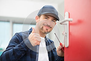 Locksmith with screwdriver holding thumbs up