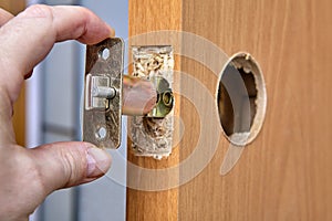 Locksmith shoves the latch Into hole of interior door