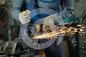 Locksmith in special clothes and goggles works in production. Metal processing with angle grinder. Sparks in