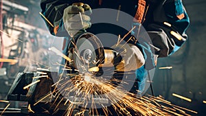 Locksmith in special clothes and goggles works in production. Metal processing with angle grinder. Sparks in photo