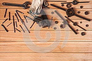 Locksmith vises, dies and taps of different diameters, a pipe wrench and work gloves on a wooden background.