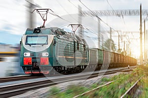Locomotive electric with a freight train at high speed rides by rail.
