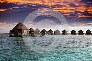 Lodges over water at the time sunset. Maldives.