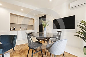 Loft with glass round black dining table with vase and open plan kitchen in contemporary design, wall mounted tv and assorted