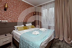 loft style bedroom interior with double bed, red brick wall, curtains