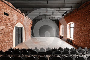 Loft style. Hall with black chairs for webinars and conferences. A huge room with large Windows, surrounded by brickwork