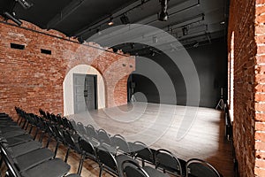 Loft style. Hall with black chairs for webinars and conferences. A huge room with large Windows, surrounded by brickwork