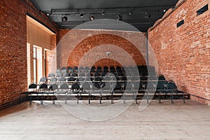 Loft style. Hall with black chairs for webinars and conferences. A huge room with large Windows, surrounded by brickwork