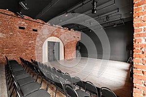 Loft style. Hall with black chairs for webinars and conferences. A huge room with large Windows, surrounded by brickwork