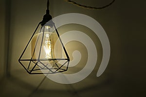 Loft style lamp hanging on a string on a wall in a room. Lighting effect of a modern light bulb