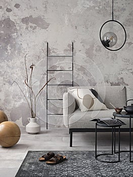 Loft style of modern apartment with grey design sofa, black coffee table, black ladder, pedant lamp, white vase, carpet, wooden
