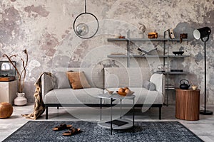 Loft style of modern apartment with grey design sofa, coffee table, bookstand, pedant lamp, carpet, decoration and elegant