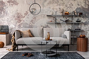 Loft style of modern apartment with grey design sofa, coffee table, bookstand, pedant lamp, carpet, decoration and elegant photo