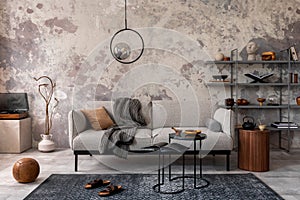 Loft style of modern apartment with grey design sofa, marble coffee table, bookstand, pedant lamp, carpet, decoration and elegant