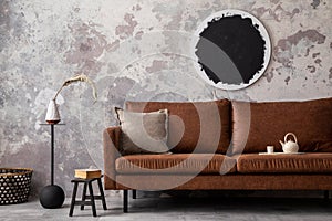 Loft style of modern apartment with mock up poster frame, brown sofa, black coffee table, gray pillow, stool with books, lamp and