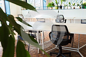 Loft style office with white brick walls and concrete columns. There is a meeting area with a  white table with black chairs