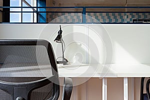 Loft style office with white brick walls and concrete columns. There is a meeting area with a  white table with black chairs