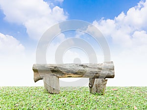 Log bench on a green grass with blue sky