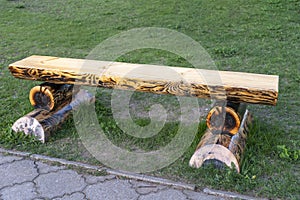 A log bench stands on a lawn in a park