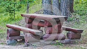 A log bench and table in the Park against a background of green grass