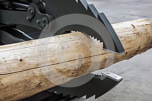 log is clamped by a manipulator arm at a sawmill