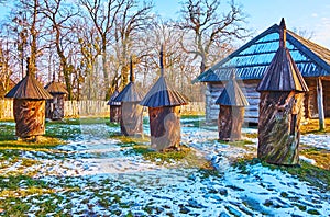 The log hives on the snowy lawn, Polissya region, Pyrohiv Skansen, Kyiv, Ukraine