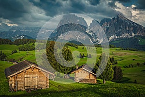 Log huts on the green meadow in the Dolomites, Italy