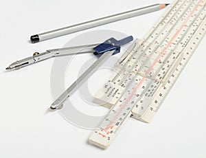 Logarithmic ruler, compasses, pencil on a white background . Stationery for engineers and students